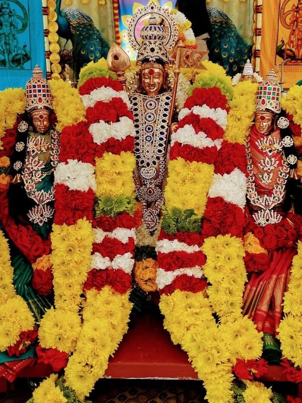 Traditional temple deities adorned in elaborate, fresh marigold and rose garlands