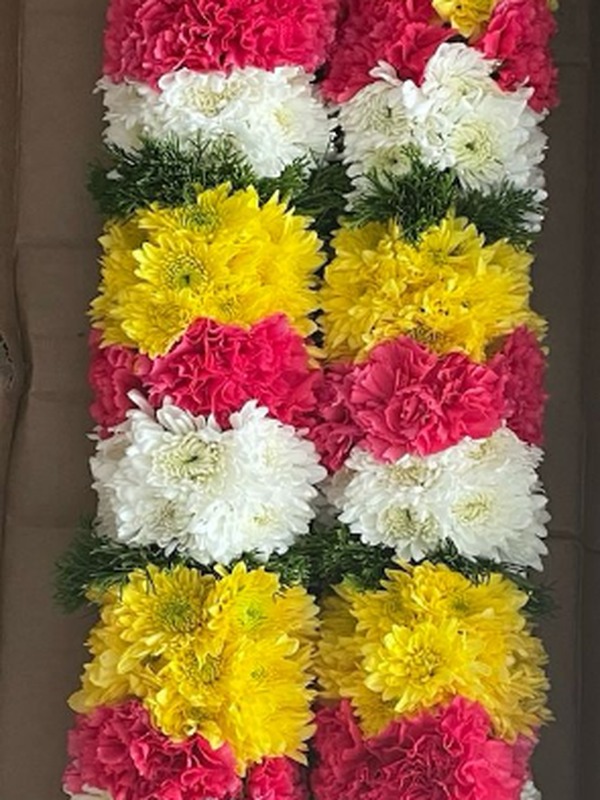 Woven garland with yellow, red, and white carnations and jasmines in box